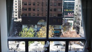 Blick aus einem Fenster auf eine Stadtansicht mit Gebäuden und Bäumen.
