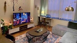 Ein modernes Wohnzimmer mit Flachbildfernseher, Essbereich und Sofa.