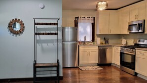A modern kitchen with stainless steel appliances, wooden flooring, and light-colored cabinetry. - KC Tiny Studio (Kansas City)