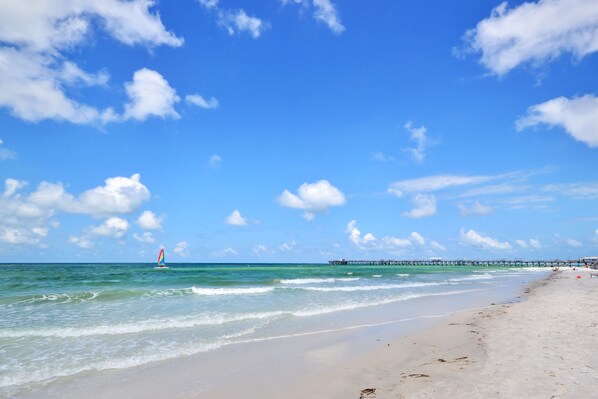 Enjoy a serene beach experience with a wide sandy shore and calm ocean waters.