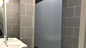Une salle de bain avec un lavabo blanc, un miroir et des carreaux gris.