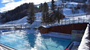 Une piscine avec des couloirs bien délimités, entourée d’une clôture en bois et agrémentée d’un petit abri.