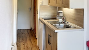 Une cuisine compacte avec des meubles de rangement en bois, un four encastré et un évier.