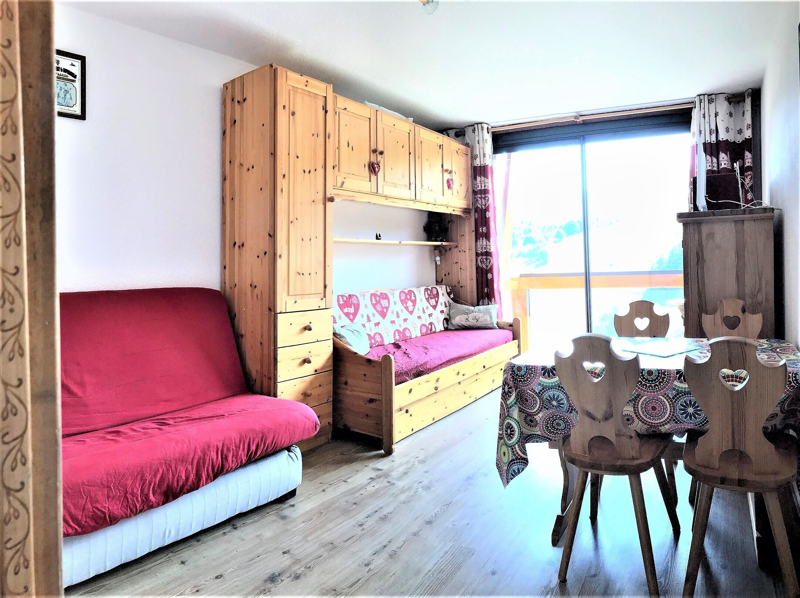 Ein gemütliches Zimmer mit einem Etagenbett, einer Couch, einem Esstisch mit Stühlen und einem großen Fenster.