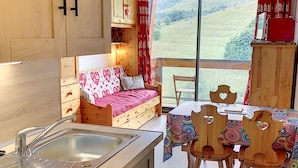 Une cuisine chaleureuse avec des meubles de rangement en bois, un évier et un coin repas comprenant une table et des chaises.