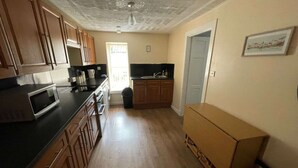 A kitchen with wooden cabinets, a microwave, a sink, and a window. - 3 Bedroom Miners Cottage - Wanlockhead D & G (Wanlockhead)