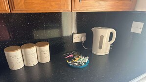 A kitchen counter with three containers labeled 'tea', 'sugar', and 'coffee', a kettle, and a bowl of tea bags. - 3 Bedroom Miners Cottage - Wanlockhead D & G (Wanlockhead)