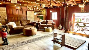 Un intérieur rustique avec des poutres en bois, un ensemble de canapés en cuir et un vélo à l’extérieur.