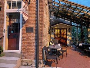A brick building with a sign reading "MURPHY'S" and a covered outdoor seating area with tables and chairs. - Private Two Bedroom - Full bath suite (Hermann)