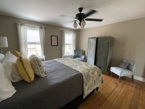 A bedroom with a bed, a ceiling fan, a chair, and a window with curtains. - Private Two Bedroom - Full bath suite (Hermann)