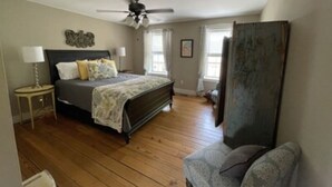 Une chambre à coucher avec un lit, une chaise, un ventilateur de plafond et une fenêtre.