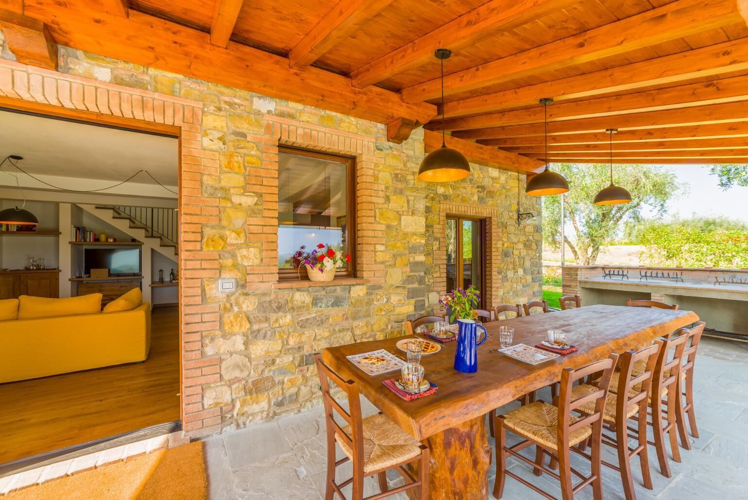 Un intérieur en pierre et en bois comprenant un coin repas, un canapé et une vue sur l’extérieur.