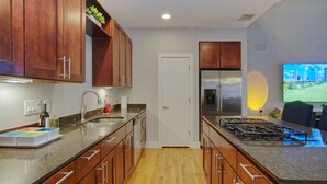 A modern kitchen with wooden cabinets, a stainless steel refrigerator, and a built-in gas stove. - Houston Heights Lux 3 story-townhouse-Rice Military (Houston)
