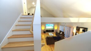 A staircase leading to a living area with a television, sofa, and coffee table. - Houston Heights Lux 3 story-townhouse-Rice Military (Houston)