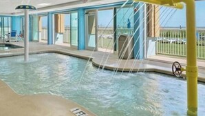 Ein Innenpool mit einem gelben Wasserspiel, großen Glaswänden und Blick ins Freie.