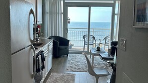Eine moderne Küche mit Meerblick, ein Essbereich mit Tisch und Stühlen sowie ein Balkon mit Geländer.