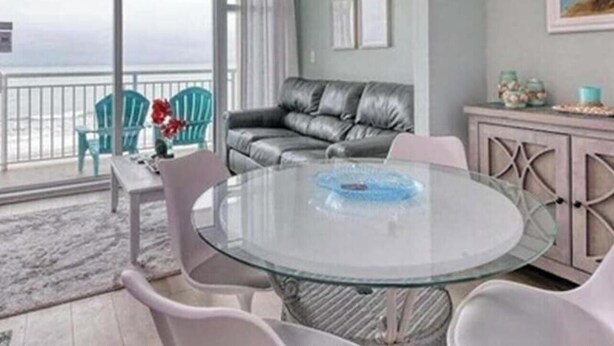 Ein Wohnzimmer mit Glastisch, Ledersofa und Meerblick.