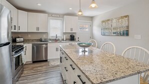 A modern kitchen with white cabinets, stainless steel appliances, a granite countertop, and pendant lighting. - Private Saltwater Pool + Spacious Yard. King Suite and Linens & Towels Included! (Villas)