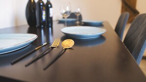 A dining table set with plates, cutlery, and wine bottles. - Modern, cozy & central - kitchen, parking space, Netflix & more (Pfaffenhofen an der Ilm)