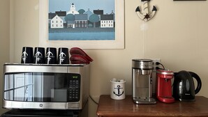 Cozinha com micro-ondas GE, cafeteira e chaleira sobre a bancada.
