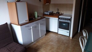 A compact kitchen with white cabinets, a built-in oven, and a small countertop. - 4-person apartment (Picherande)