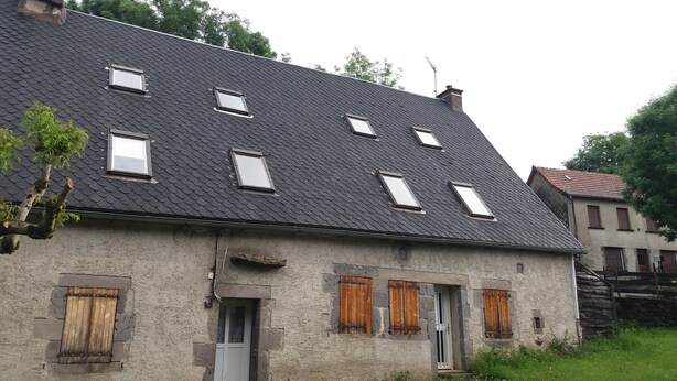 A two-story house with a steeply pitched roof, multiple small windows, and a door with wooden shutters. - 4-person apartment (Picherande)