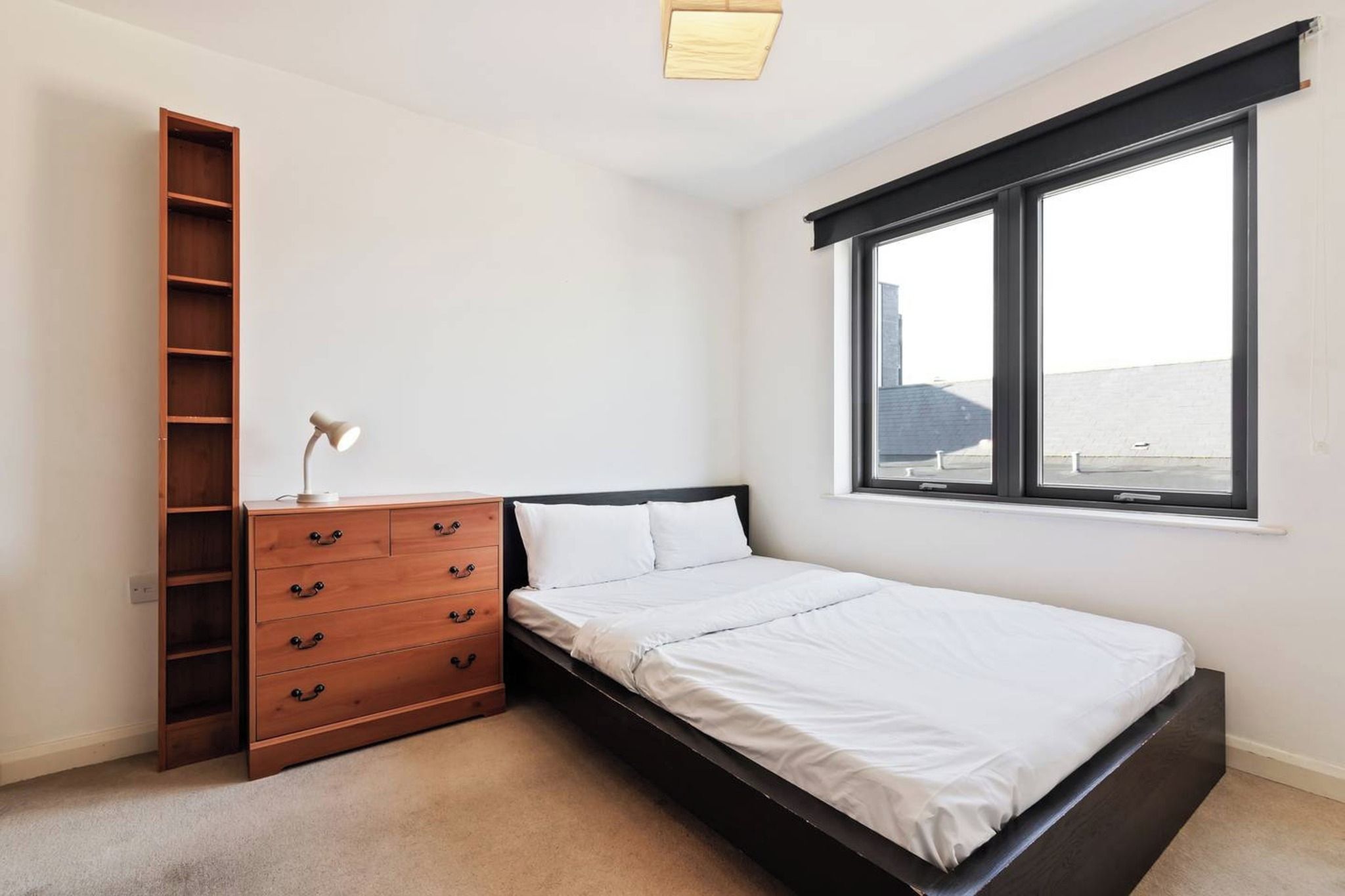 Un dormitorio con cama, cómoda de madera, escritorio y ventana.