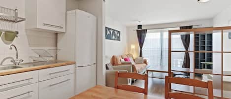 A modern kitchen with white cabinets, a wooden countertop, and a dining area with a wooden table and chairs.