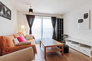 A modern living room with a sofa, a coffee table, and a TV stand.