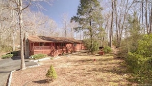A rustic cabin with a porch, surrounded by trees and a well-maintained lawn. - Nature at it's Best (Old Fort)
