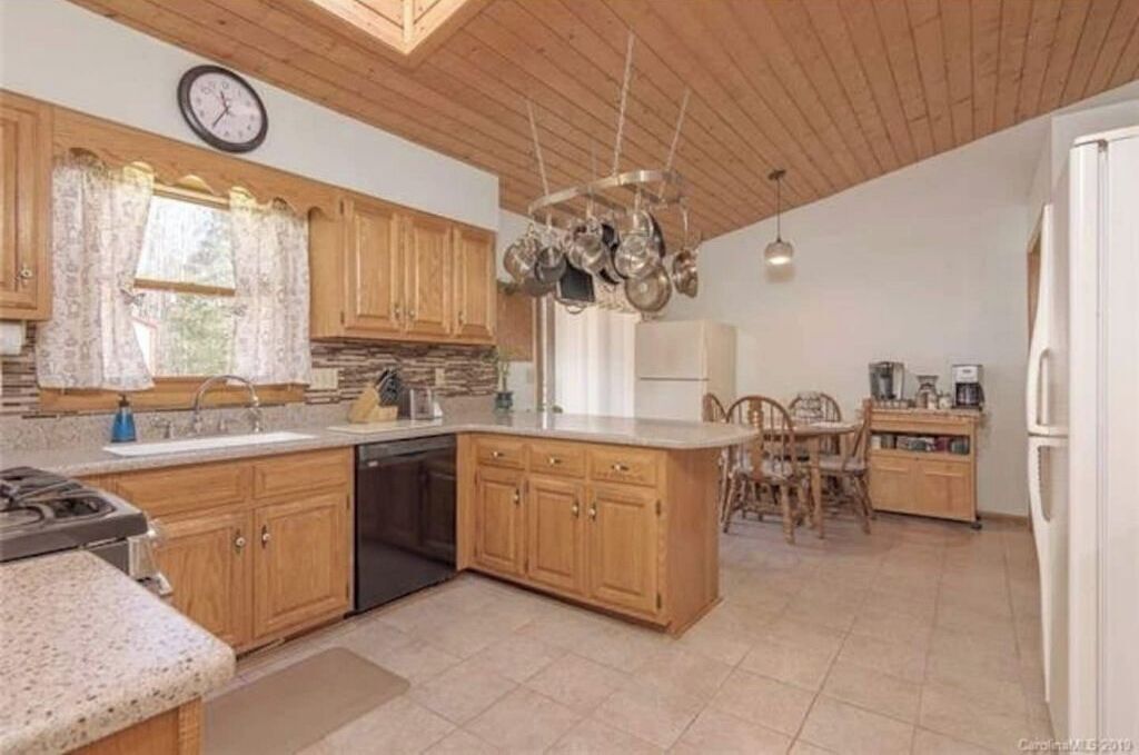 Une cuisine avec des meubles de rangement en bois, un îlot central et un coin repas avec des chaises.