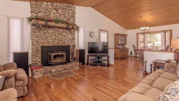 A cozy living room with a stone fireplace, wooden flooring, a television, and comfortable seating. - Nature at it's Best (Old Fort)