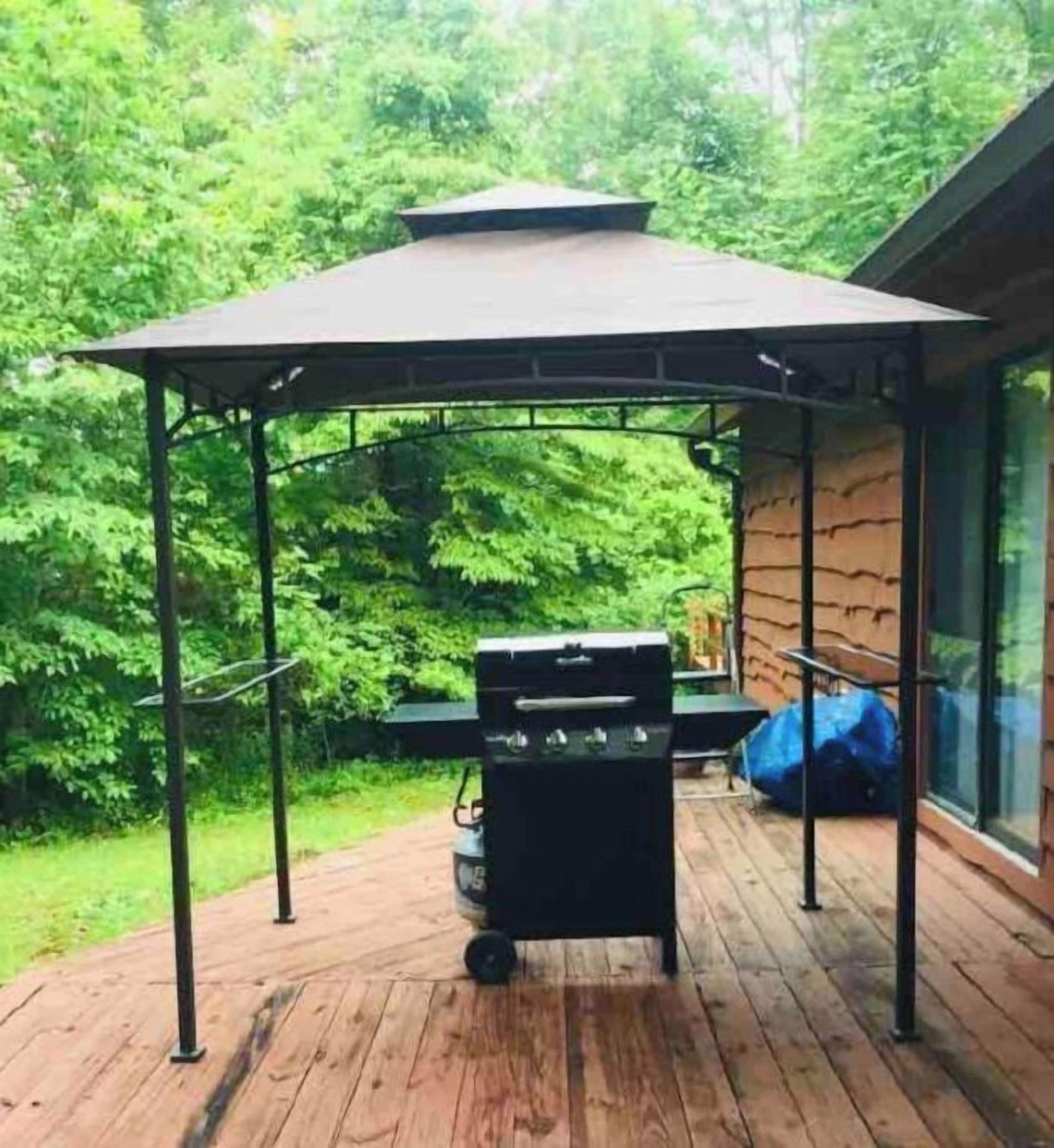 A covered outdoor grill area with a canopy, a barbecue grill, and a table.