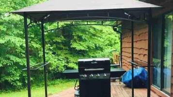 A covered outdoor grill area with a canopy, a barbecue grill, and a table.