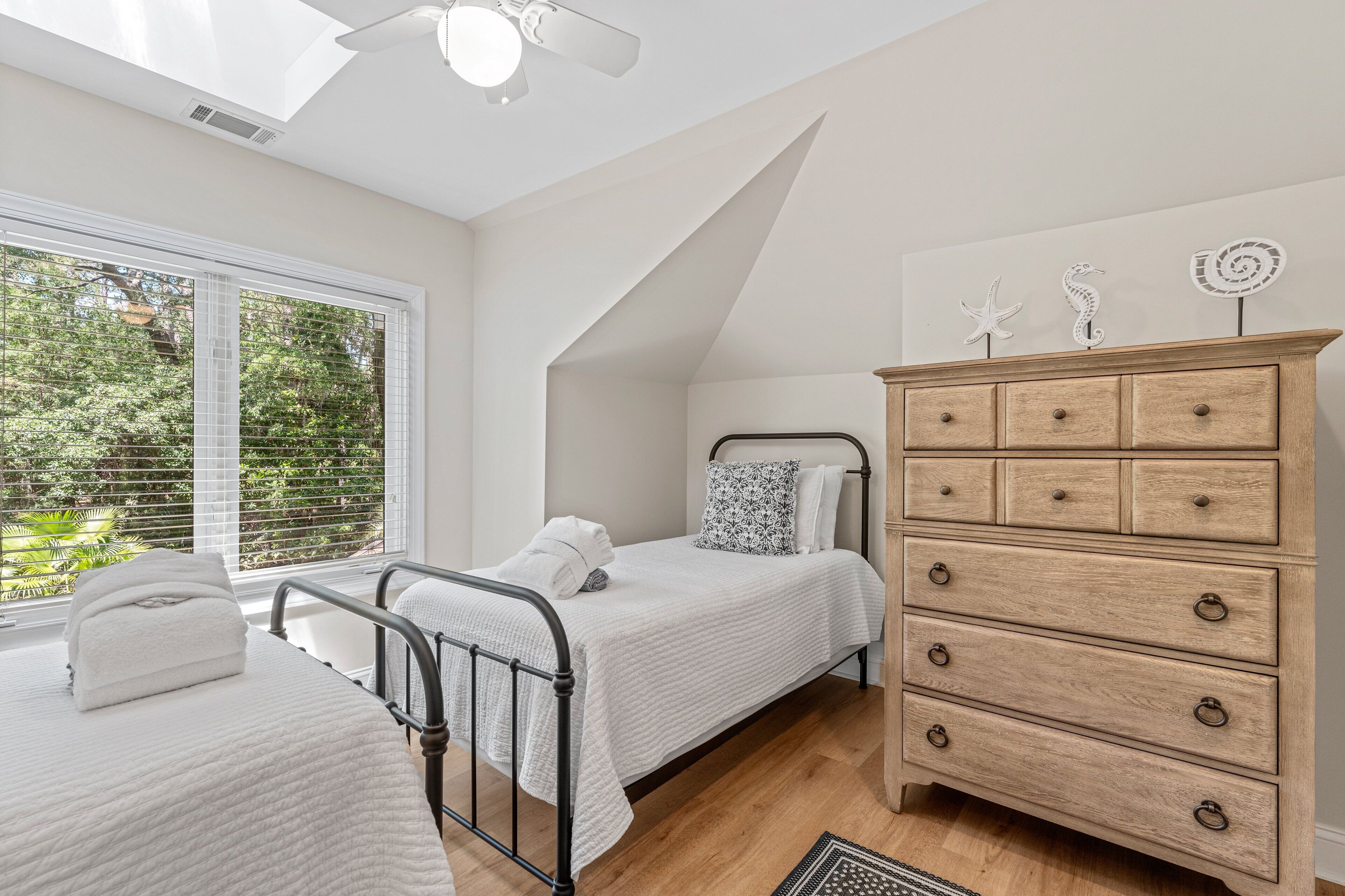 A bedroom with a bed, a dresser, and a skylight.