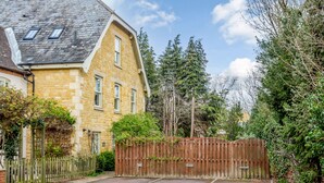 A residential property with a stone facade, a wooden fence, and a gravel driveway. - Jasmine Cottage (Chipping Campden)
