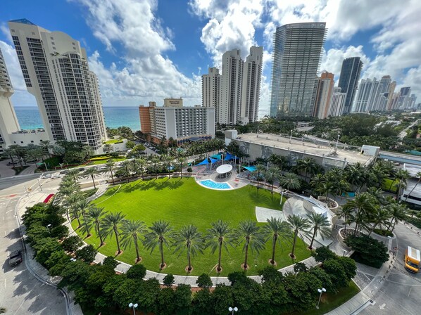 Un hôtel de grande hauteur doté d’une piscine entourée de palmiers et offrant une vue sur l’océan.