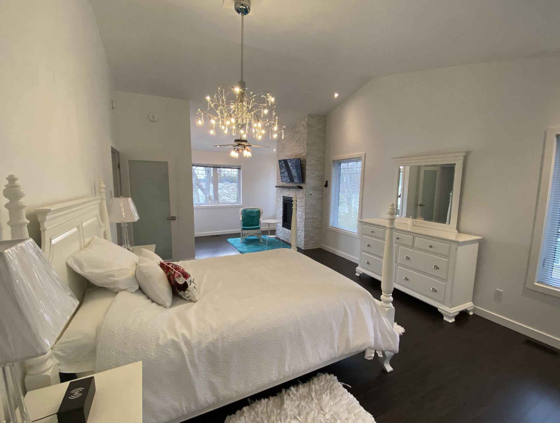 Ein geräumiges Schlafzimmer mit einem großen Bett, einem Schminktischchen, einer Kommode und einer Chandelier.