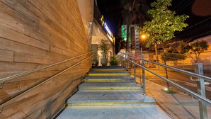 Una escalera conduce a un edificio con fachada de madera y un letrero de neón.