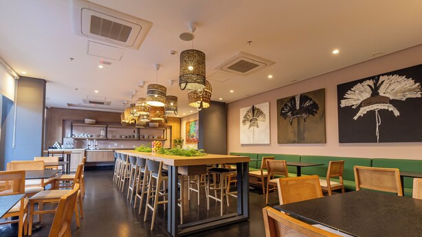 Un interior de restaurante moderno con una zona de bar central, sillas y mesas de madera.