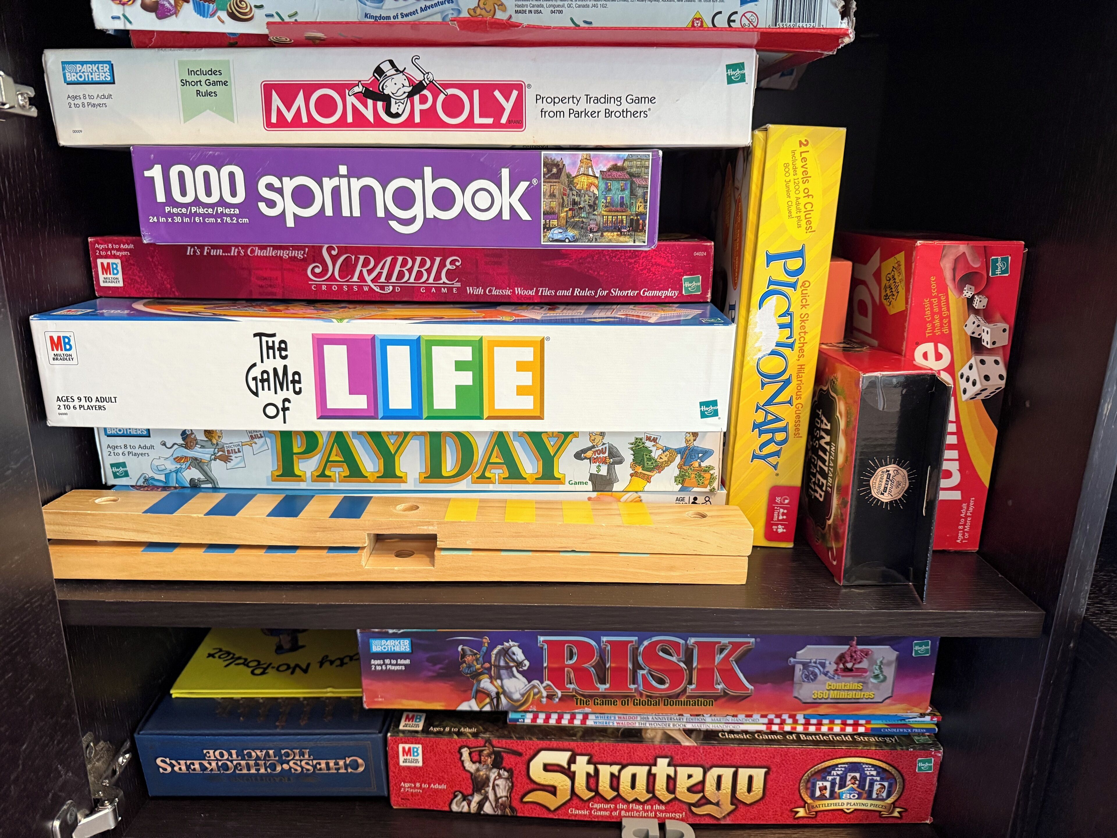 Ein Regal mit verschiedenen Gesellschaftsspielen, darunter Monopoly, Scrabble und Risiko.