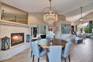 A spacious living room with a fireplace, a large round dining table, and comfortable seating. - Luxury Sedona Oasis w/ Epic Red Rock Views & Hot Tub - Close to Everything! (Sedona)