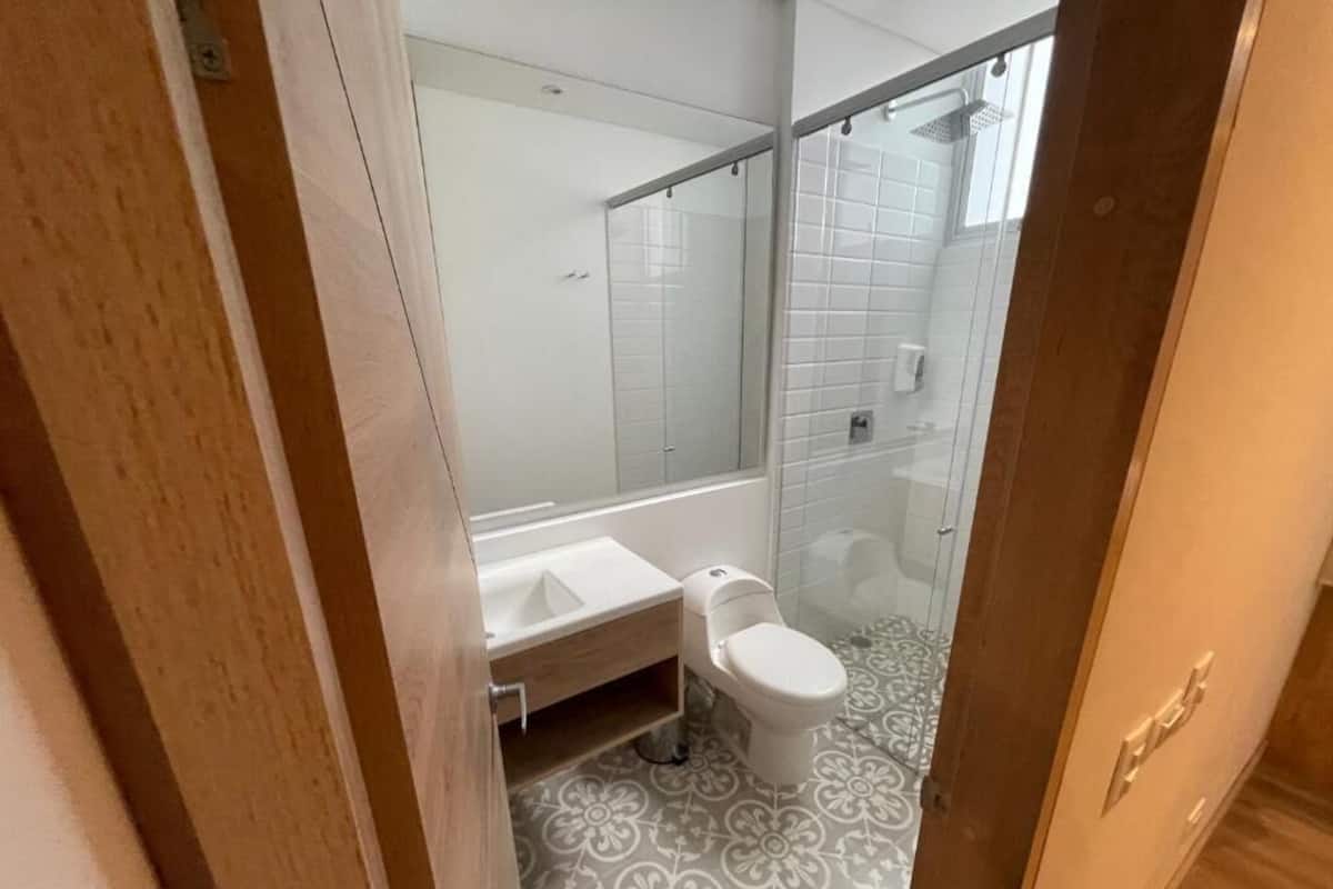 A bathroom with a glass shower enclosure, a white toilet, and a sink.