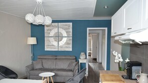 A modern living room with a grey sofa, a small round table, and a kitchen area with a microwave and coffee maker. - Beautiful apartment T3, private parking "Au logis de Pézenas". (Pézenas)