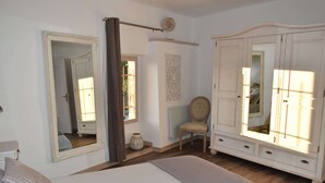 A bedroom with a large bed, a chair, a wardrobe, and a mirror. - Beautiful apartment T3, private parking "Au logis de Pézenas". (Pézenas)
