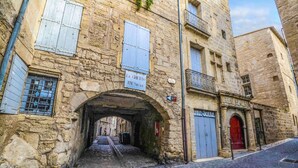 A stone building with a sign reading "Le Ghetto XIVe Siecle" and a red door. - Beautiful apartment T3, private parking "Au logis de Pézenas". (Pézenas)