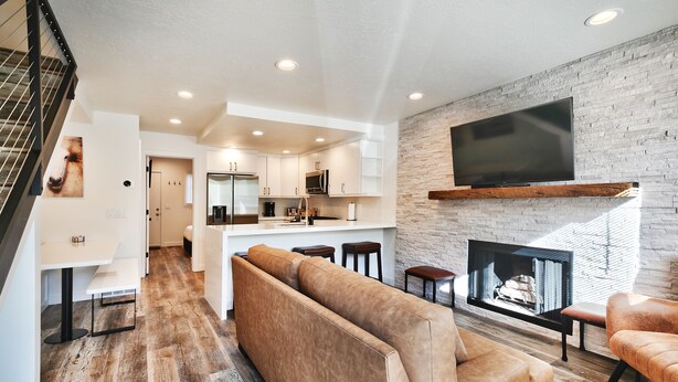 A modern living room with a large sectional sofa, a fireplace, and a kitchen in the background. - City Park - Walk to Main Street - Old Town (Park City)