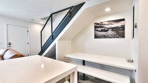 A modern loft bedroom with a sloped ceiling, a staircase with a metal railing, a white desk, and a large landscape painting on the wall. - City Park - Walk to Main Street - Old Town (Park City)