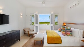 Ein Schlafzimmer mit Bett, Fernseher, Schreibtisch, Stuhl und Blick ins Freie.
