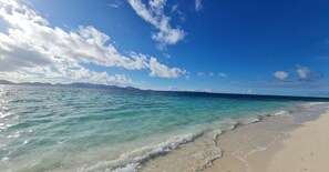 Ein Strand mit klarem türkisblauem Wasser und sandigem Ufer.